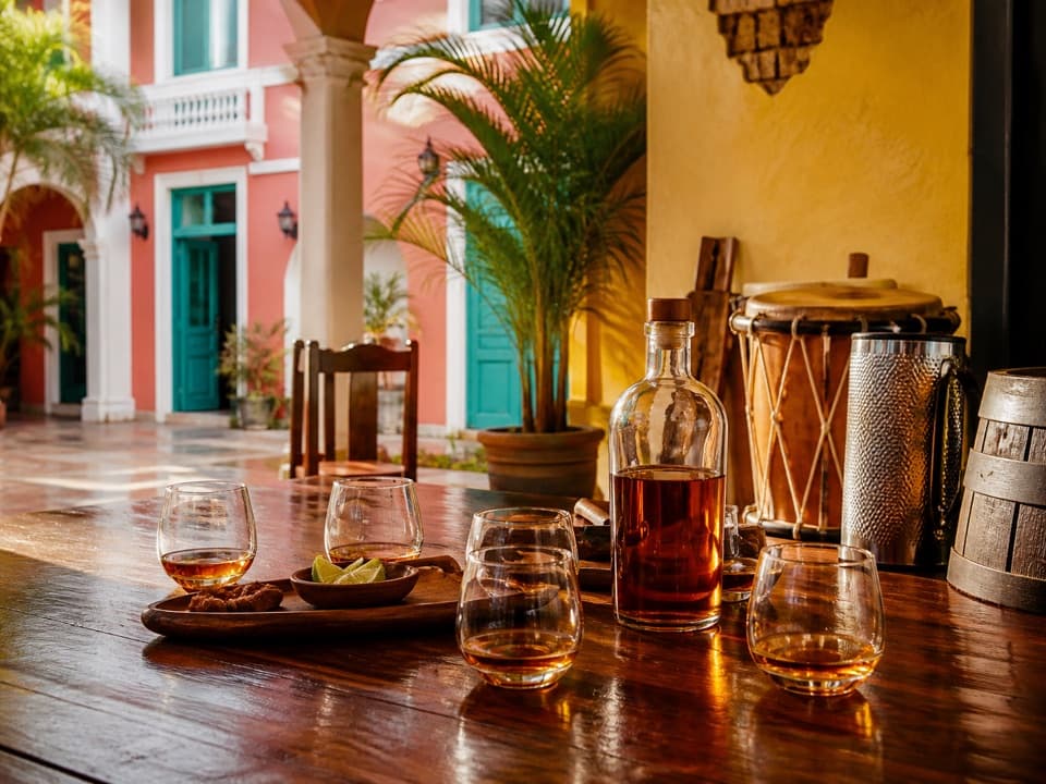 Mesa de degustación con ron ámbar, tambora y güira en un patio colonial colorido de Puerto Plata.
