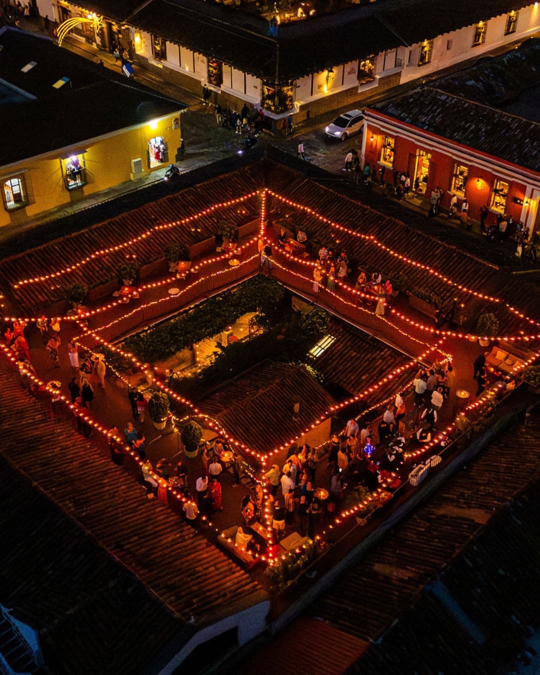 El patio colonial de Casa Troccoli de noche, visto desde arriba y rodeado de luces cálidas.